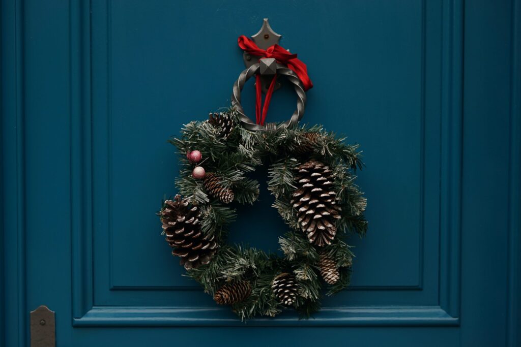 Christmas wreath with pinecones on teal door