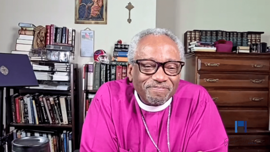 Clergyman in magenta shirt seated in study