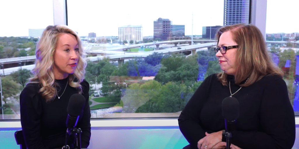 Two women recording podcast with city view