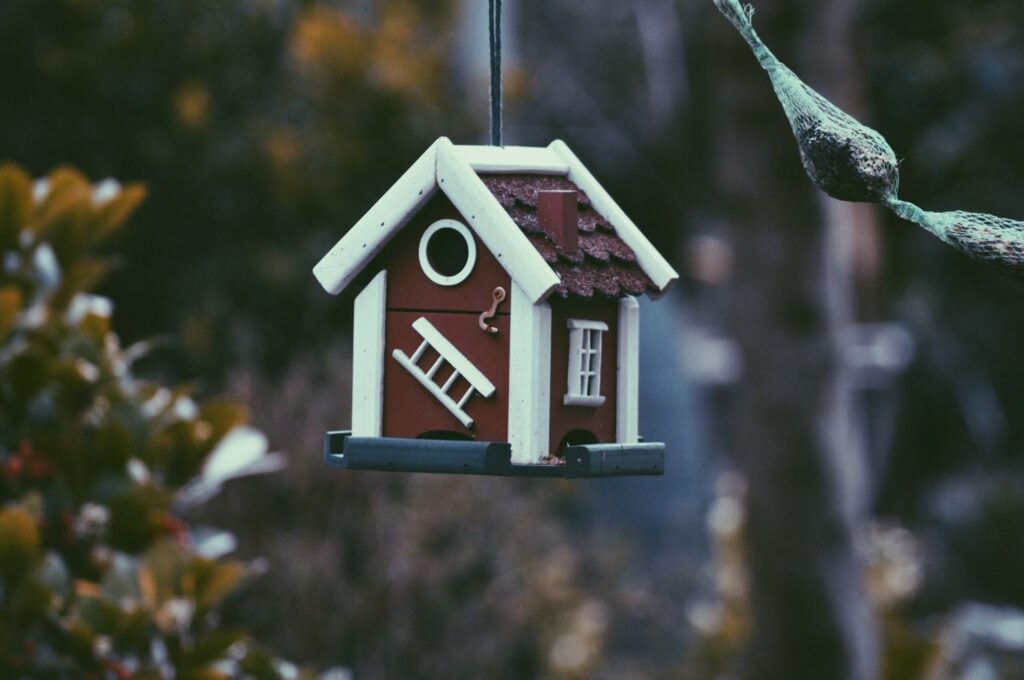 Decorative wooden birdhouse hanging in garden