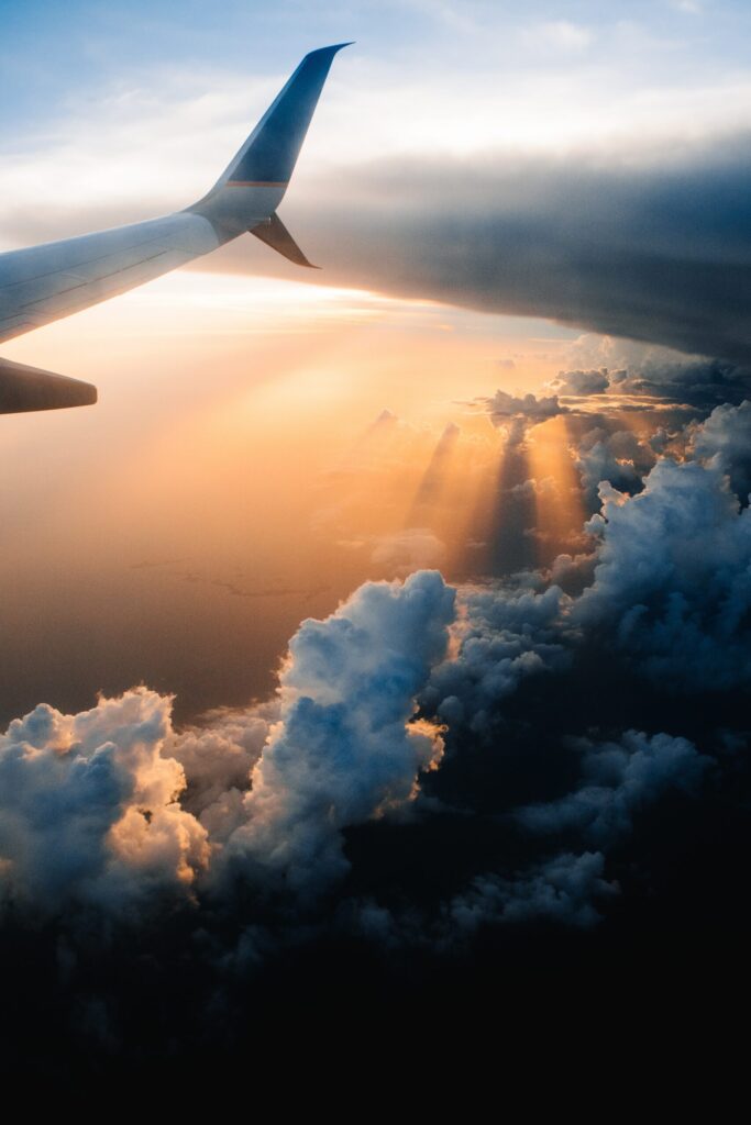 Airplane wing above clouds at sunset