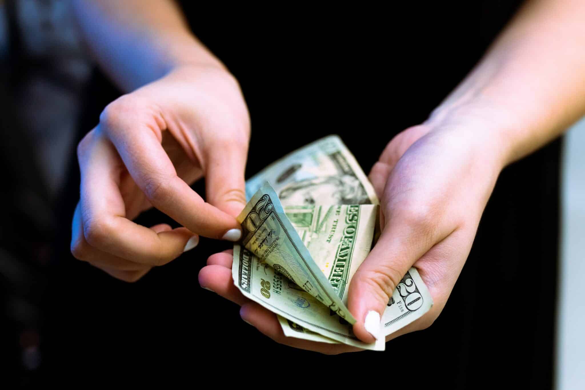 Hands counting twenty-dollar bills close-up