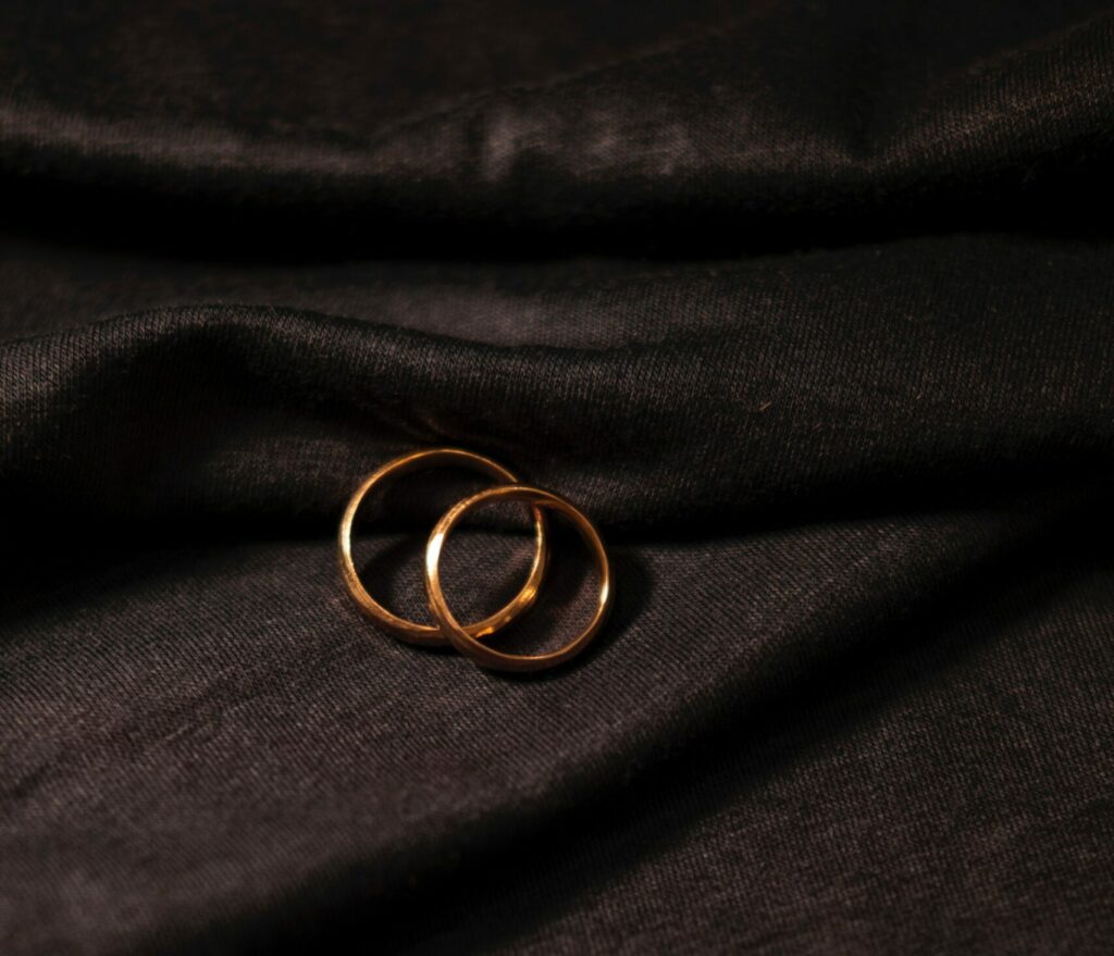 Two gold wedding rings on dark fabric