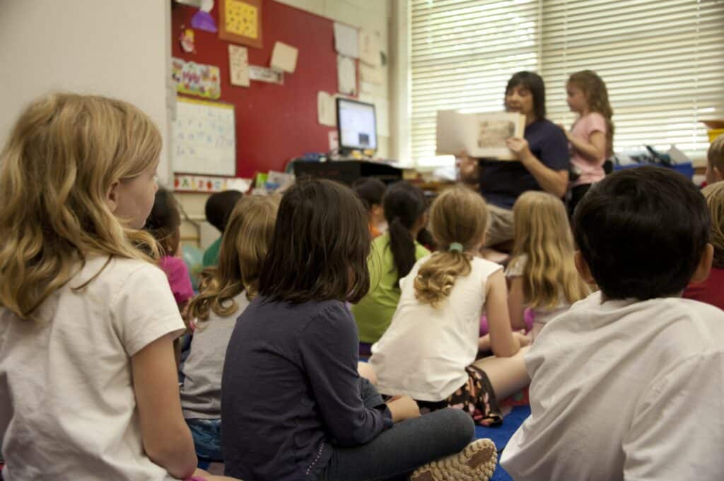 Teacher reading book to children in classroom