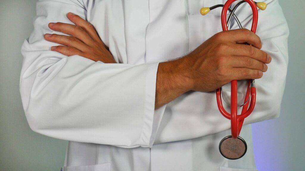 Doctor holding red stethoscope with arms crossed