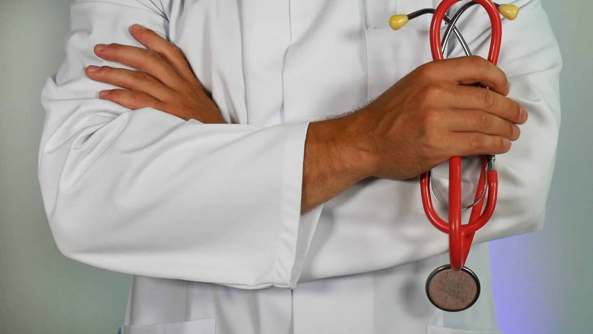 Doctor holding red stethoscope with arms crossed