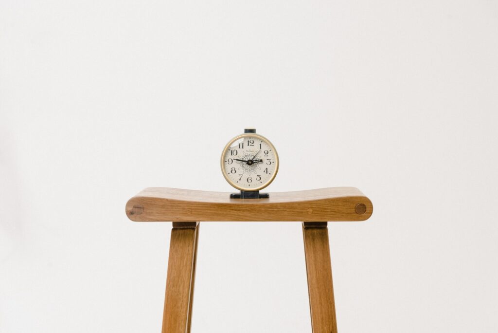 Analog alarm clock on wooden stool