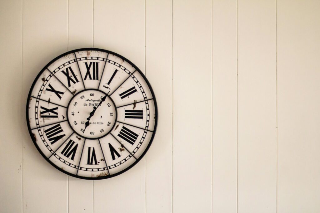 Vintage Roman numeral wall clock on paneled wall