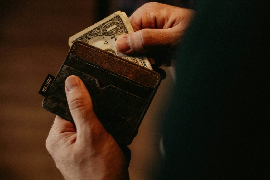 Hands placing cash into brown leather wallet
