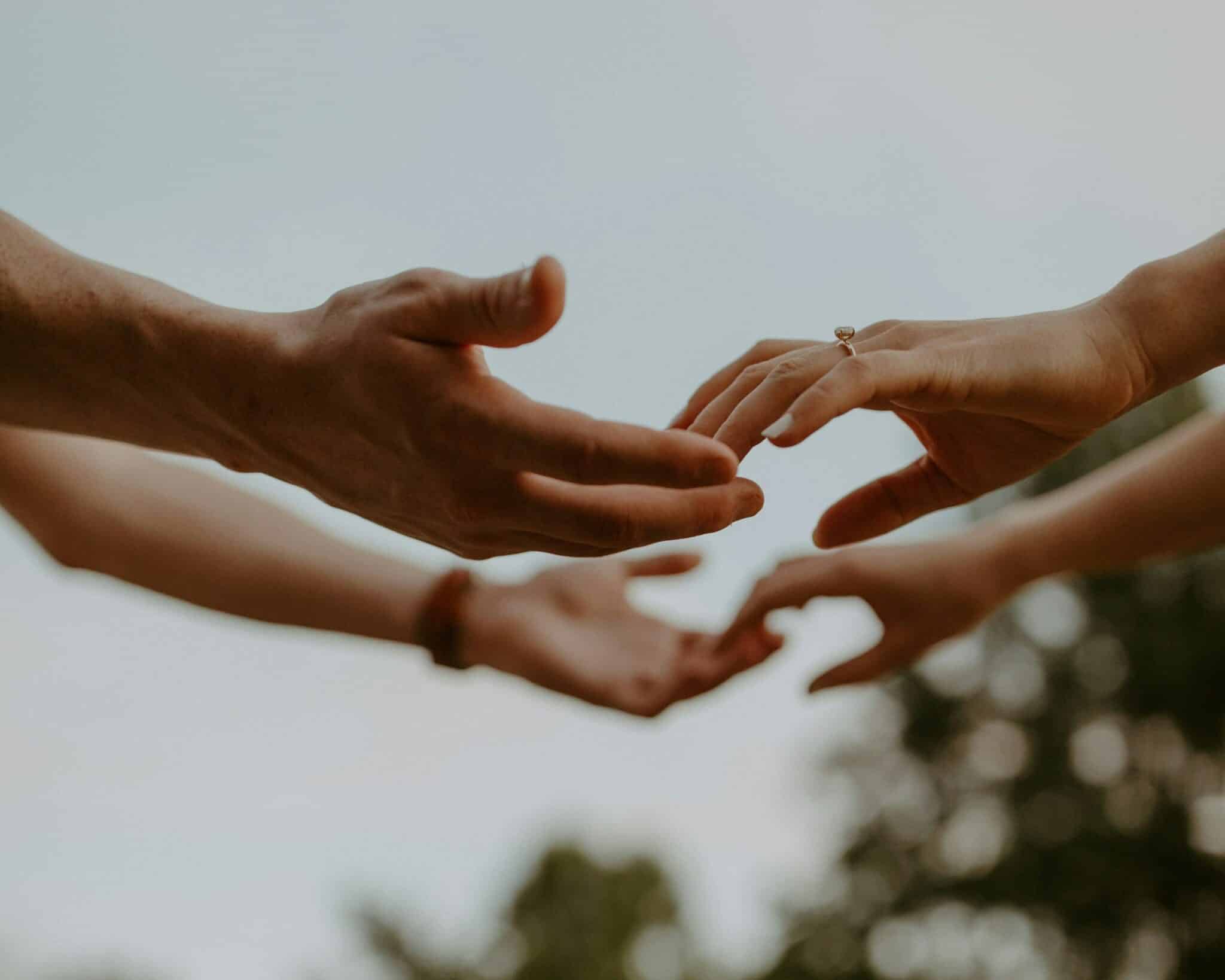 Couple reaching hands with engagement ring visible