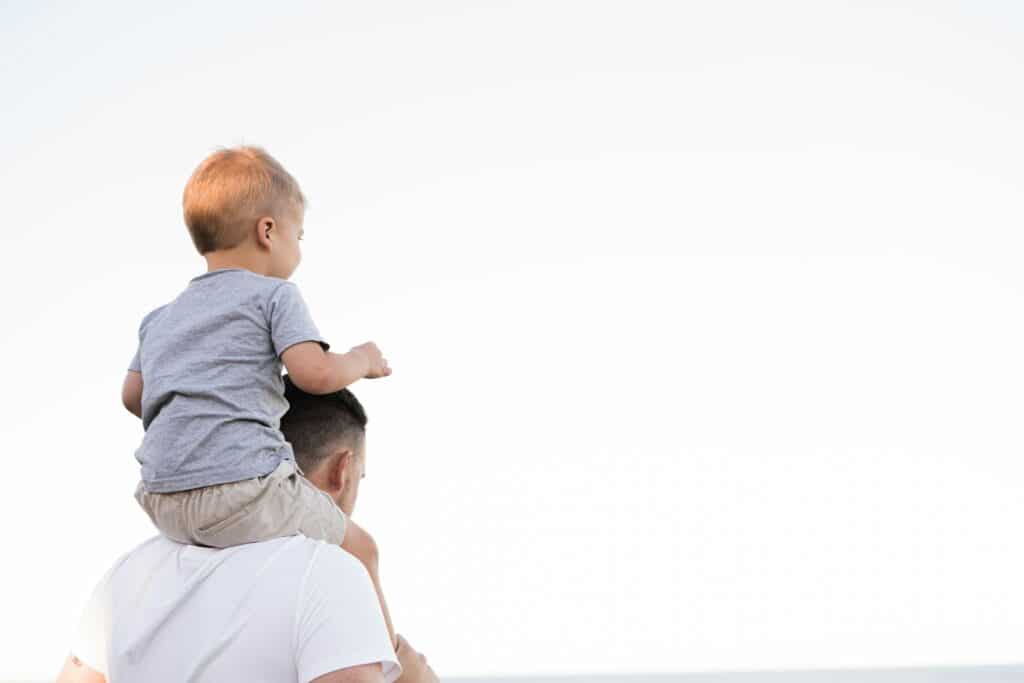 Father carrying young son on shoulders outdoors