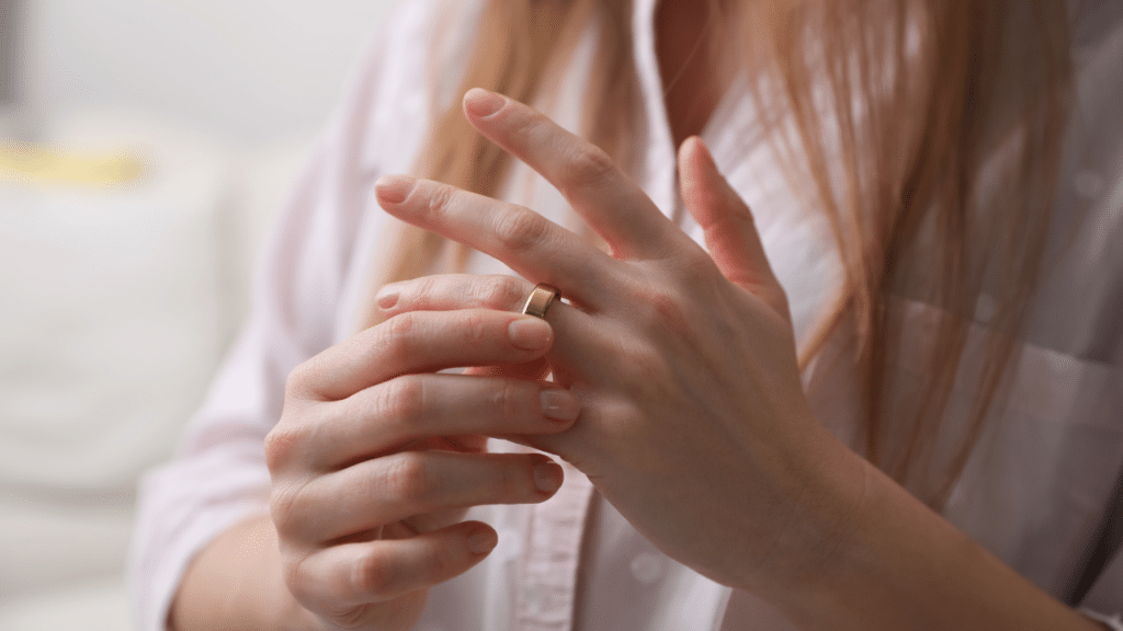 Woman removing gold wedding ring from finger