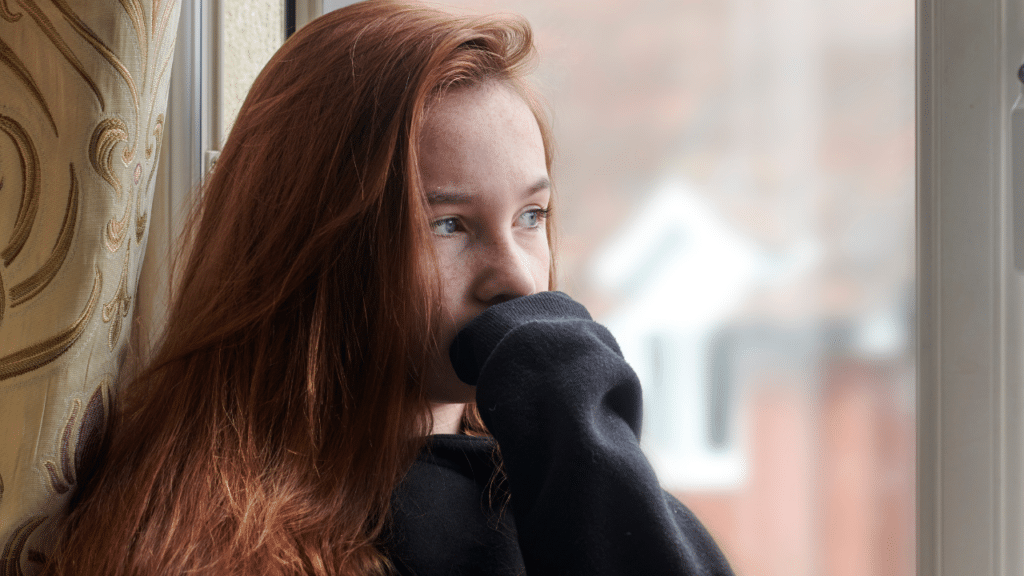 Young woman gazing thoughtfully out a window