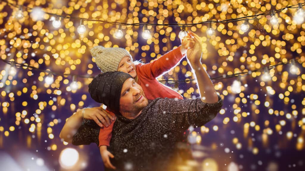 Father and child under festive string lights