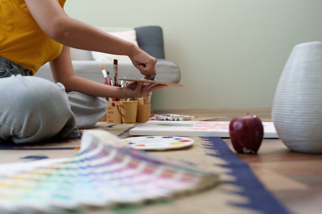 Person painting on canvas with art supplies nearby
