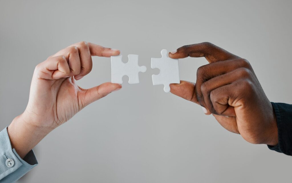 Two hands connecting puzzle pieces together