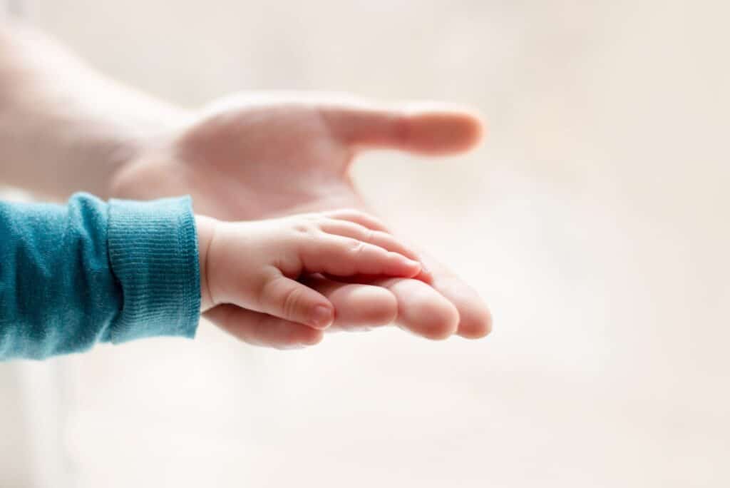 Baby's hand resting on adult's open palm