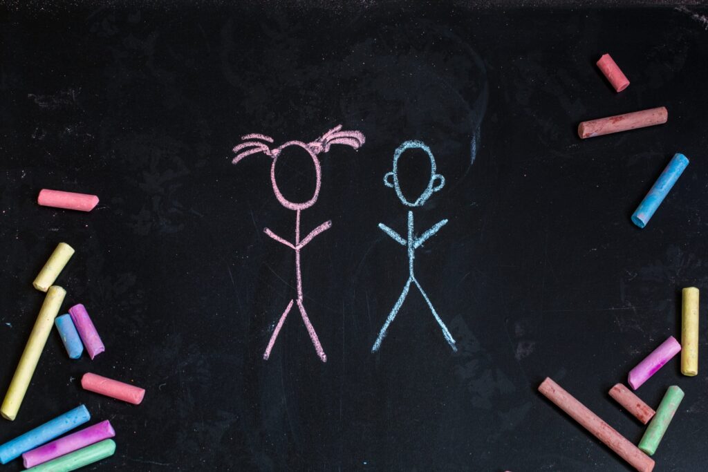 Pink and blue stick figures on chalkboard