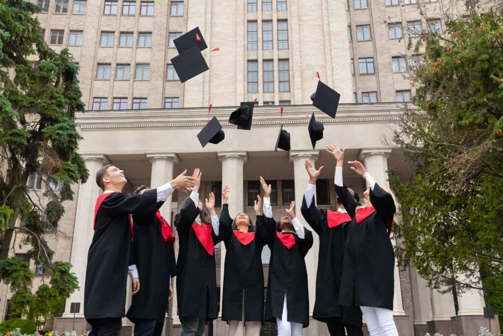 Graduates tossing caps in front of university building