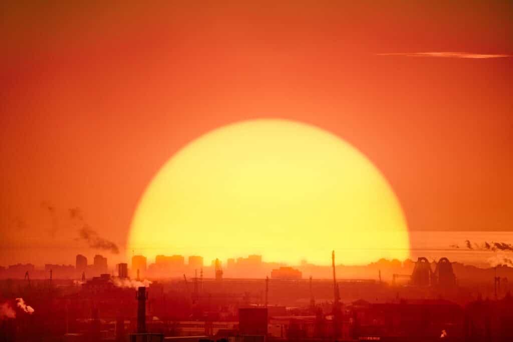 Massive sun setting over smoky industrial skyline