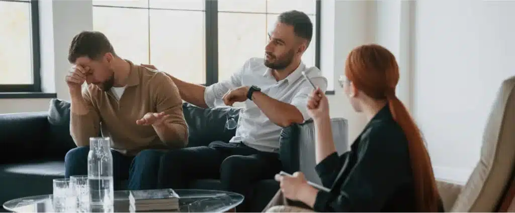 Therapist counseling two men during emotional conversation