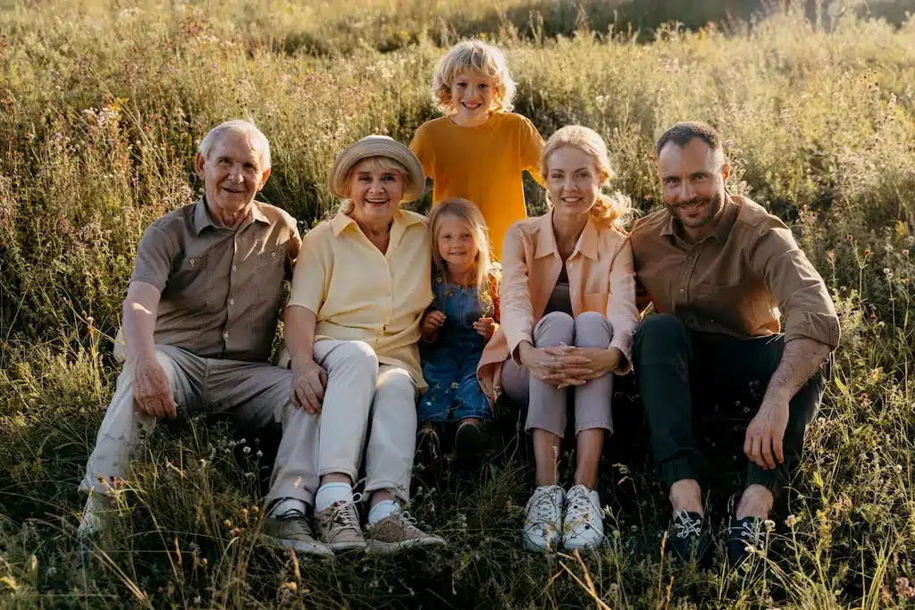 Multigenerational family sitting in sunny grassy field