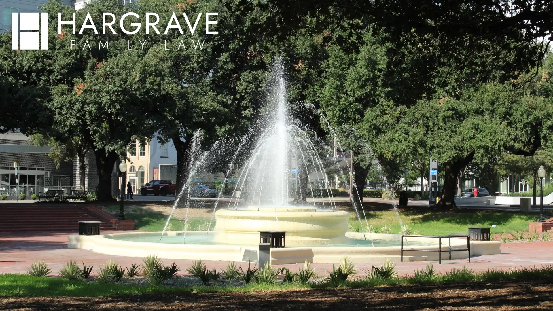 A fountain surrounded by shade trees in a downtown Dallas park in Texas, where parents resolve conservatorship and child custody arrangements.